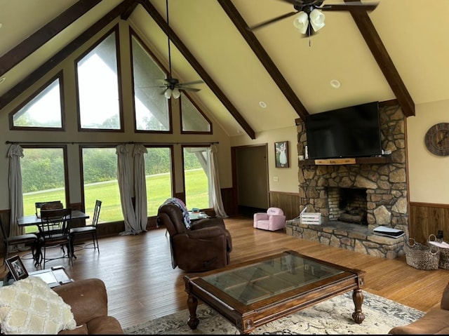 living room featuring ceiling fan, wood-type flooring, a fireplace, and wooden walls