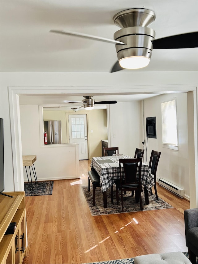 dining area featuring light wood-type flooring, a wealth of natural light, and a baseboard heating unit