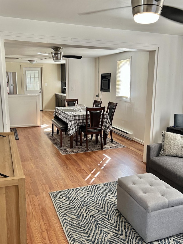 dining room with ceiling fan, wood-type flooring, and a baseboard heating unit