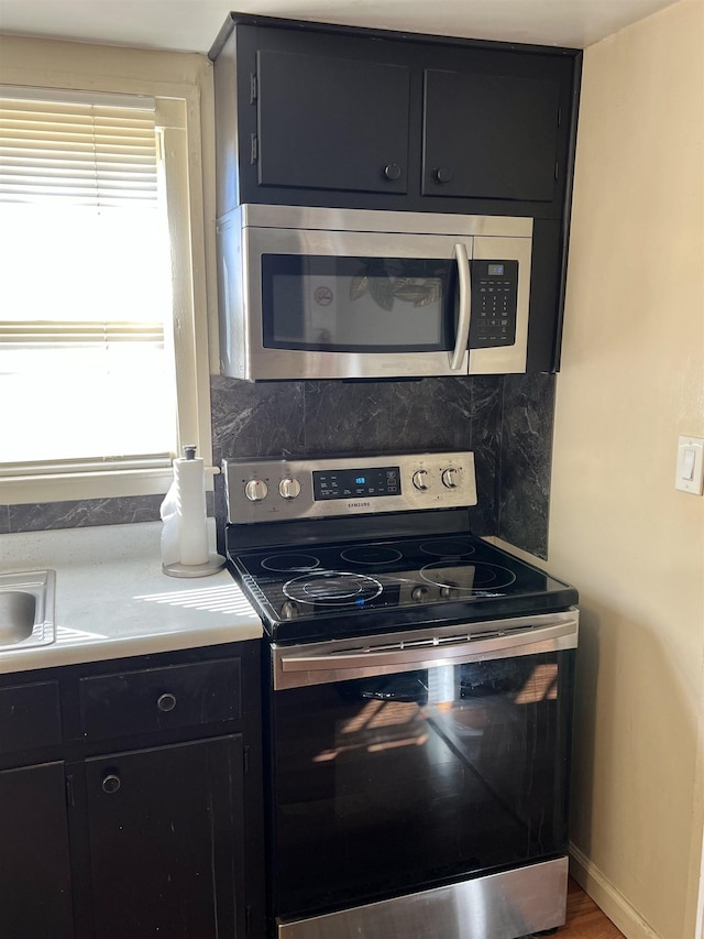 kitchen with decorative backsplash, appliances with stainless steel finishes, and hardwood / wood-style floors