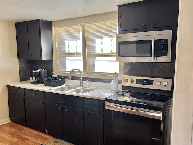 kitchen with tasteful backsplash, sink, hardwood / wood-style floors, and appliances with stainless steel finishes