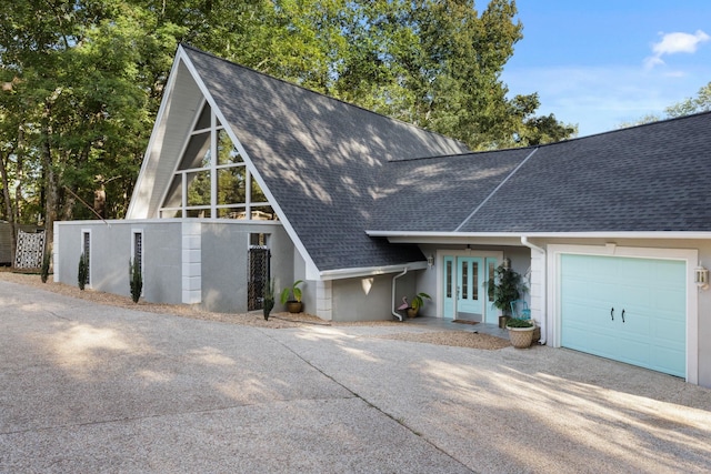 a-frame home featuring a garage, french doors, roof with shingles, and driveway