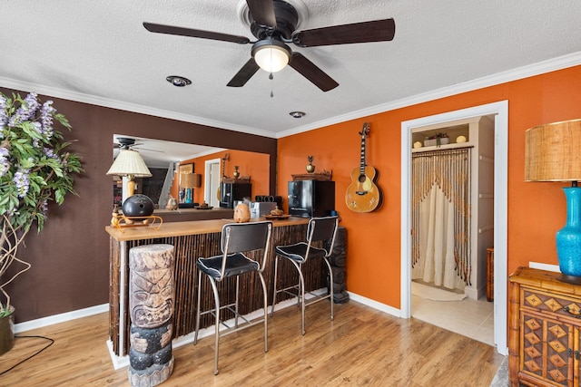 bar featuring a textured ceiling, light wood-type flooring, fridge, and ornamental molding