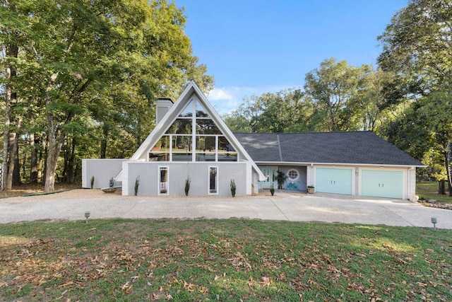 a-frame home featuring a garage, driveway, a front lawn, and a chimney