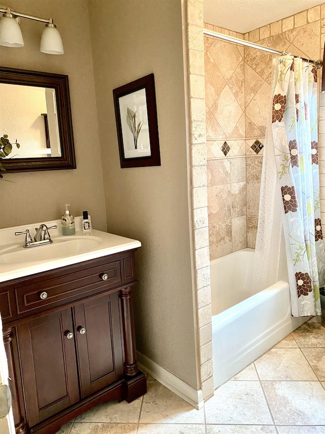  - full bath featuring vanity, shower / bath combo with shower curtain, tile patterned floors, and baseboards