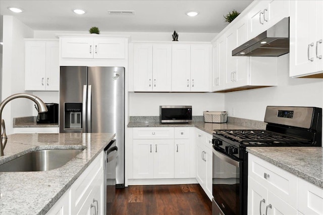  - kitchen with stainless steel appliances, under cabinet range hood, a sink, dark wood-style flooring, and white cabinetry