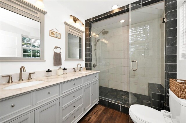  - full bathroom with toilet, a shower stall, wood finished floors, and double vanity