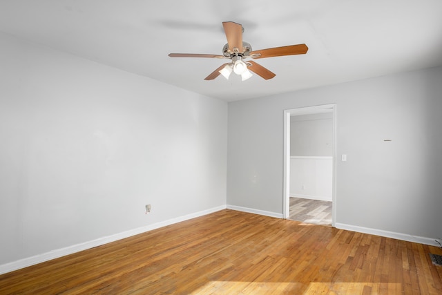 empty room with visible vents, a ceiling fan, light wood-type flooring, and baseboards