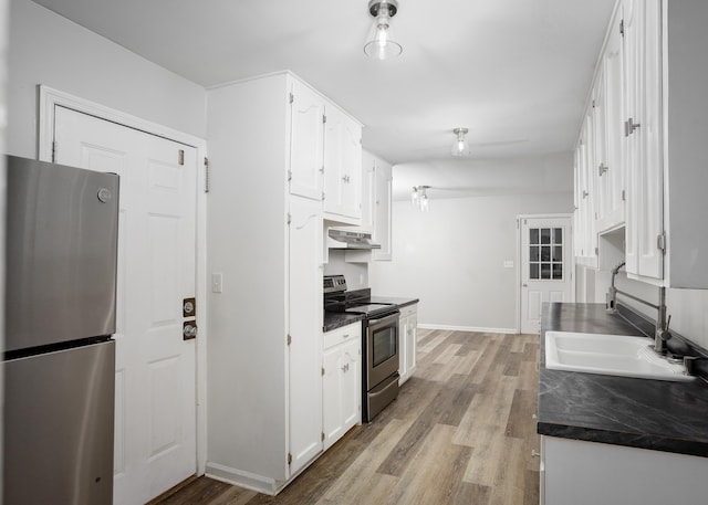 kitchen featuring white cabinetry, dark countertops, appliances with stainless steel finishes, and a sink