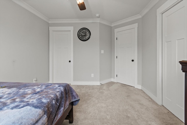 carpeted bedroom with crown molding, baseboards, and a ceiling fan
