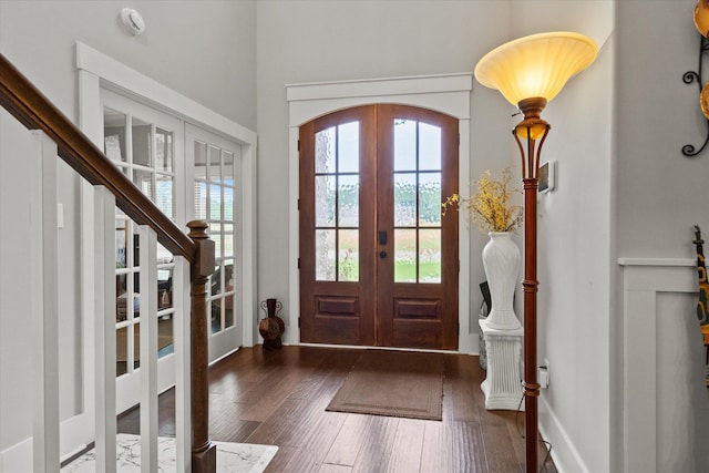 entrance foyer with french doors, healthy amount of natural light, wood finished floors, and arched walkways