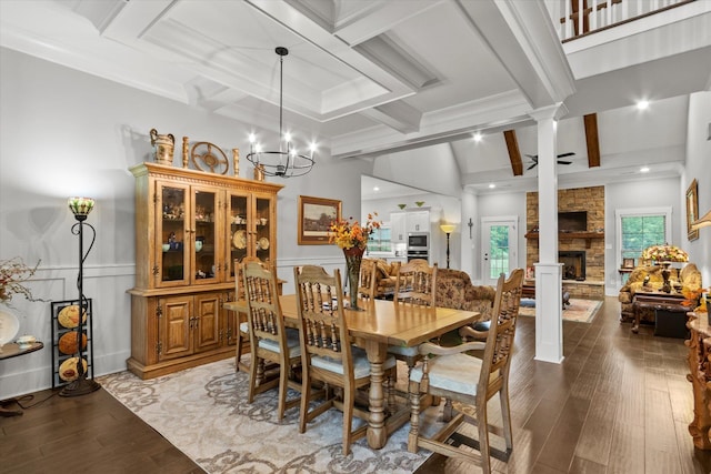 dining area with beamed ceiling, light wood-style floors, a stone fireplace, coffered ceiling, and a chandelier