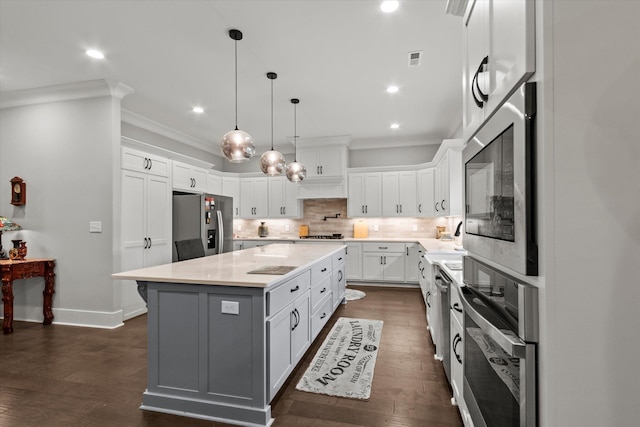 kitchen featuring appliances with stainless steel finishes, crown molding, light countertops, white cabinetry, and dark wood-style flooring