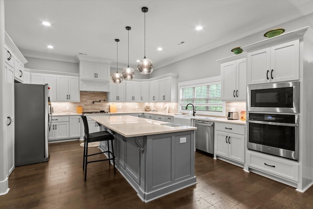 kitchen featuring stainless steel appliances, light countertops, crown molding, backsplash, and a kitchen island