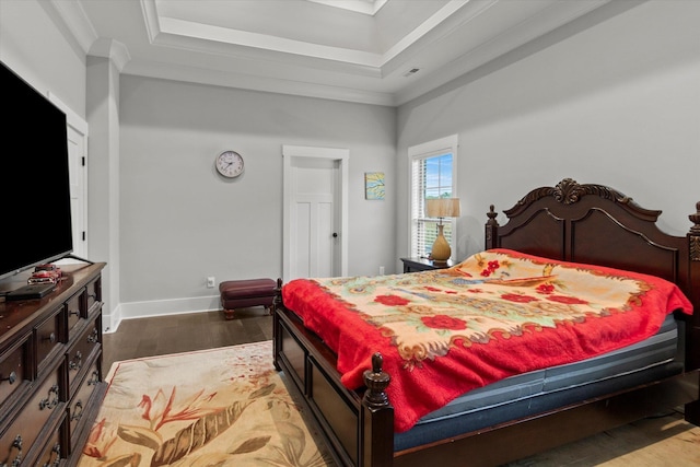 bedroom featuring a raised ceiling, wood finished floors, baseboards, and ornamental molding