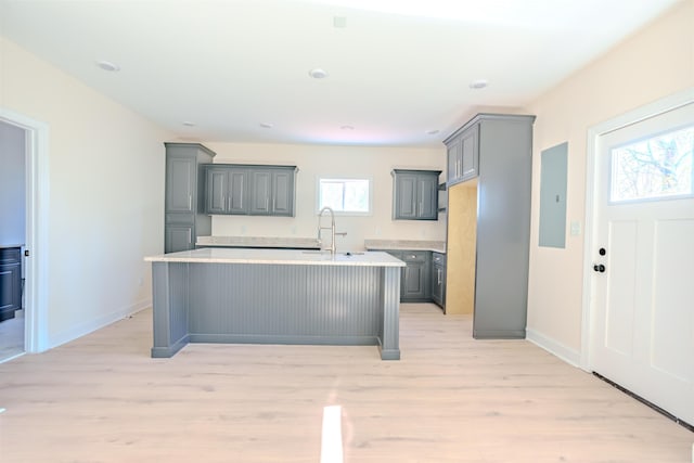  - kitchen featuring gray cabinets, light countertops, light wood-type flooring, and a kitchen island with sink