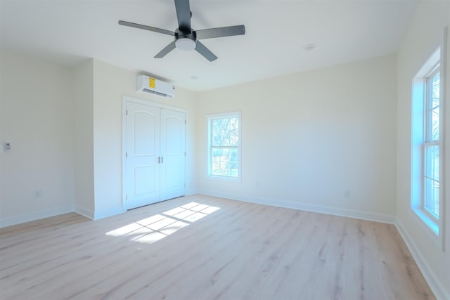  - unfurnished bedroom with a wall unit AC, light wood finished floors, and multiple windows