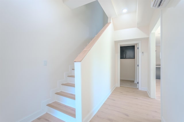  - staircase featuring wood finished floors, an AC wall unit, and recessed lighting