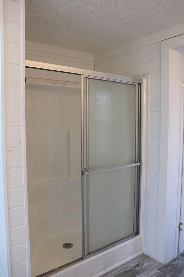 bathroom with a stall shower, a textured ceiling, and wood finished floors