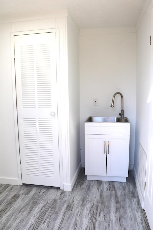 bathroom featuring baseboards, a sink, and wood finished floors