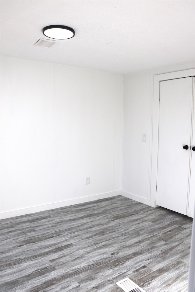 spare room with visible vents, baseboards, and wood finished floors