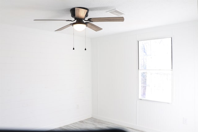 spare room featuring visible vents, ceiling fan, and wood finished floors