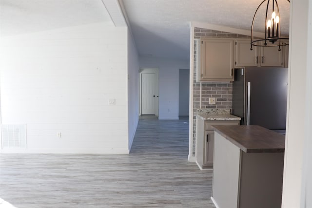 kitchen with tasteful backsplash, lofted ceiling, visible vents, light wood-style flooring, and freestanding refrigerator