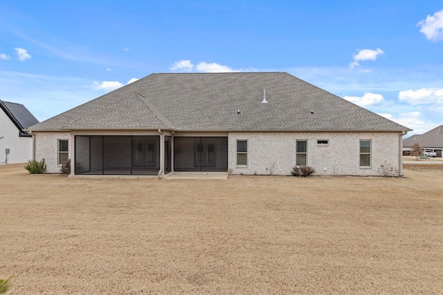 rear view of property featuring brick siding, roof with shingles, and a sunroom