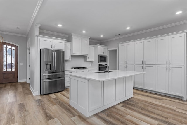 kitchen with light countertops, appliances with stainless steel finishes, arched walkways, white cabinetry, and a sink