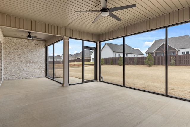 unfurnished sunroom featuring plenty of natural light, a ceiling fan, and a residential view