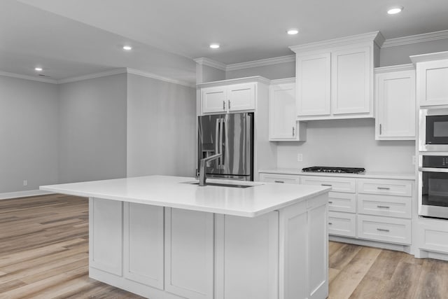 kitchen featuring white cabinets, appliances with stainless steel finishes, light wood-style floors, and a sink