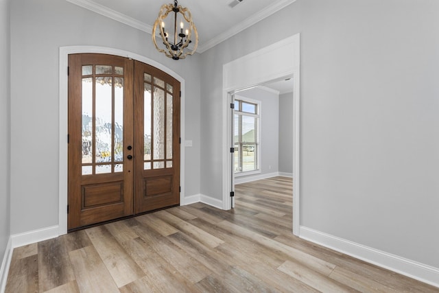 entrance foyer with wood finished floors, crown molding, french doors, and arched walkways