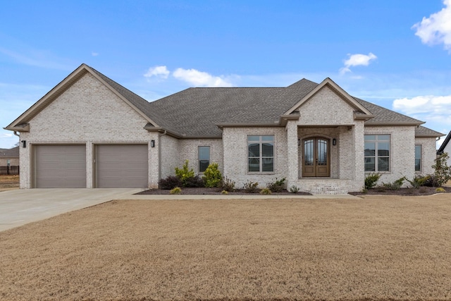 view of front facade with brick siding, driveway, a shingled roof, and an attached garage