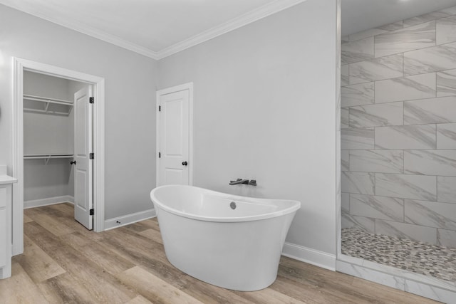 bathroom with wood finished floors, baseboards, a soaking tub, a tile shower, and crown molding