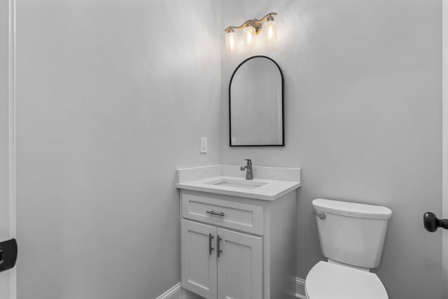 bathroom with baseboards, toilet, and vanity