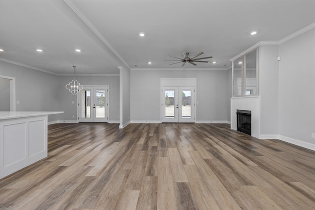 unfurnished living room featuring light wood-type flooring, french doors, a large fireplace, and a healthy amount of sunlight