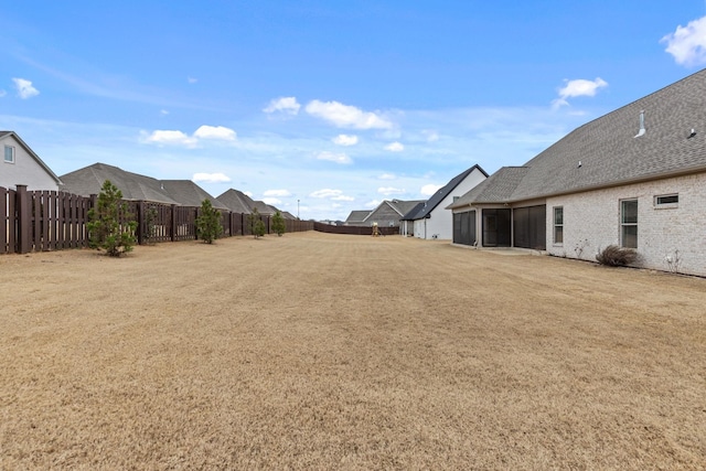 view of yard featuring a fenced backyard and a sunroom