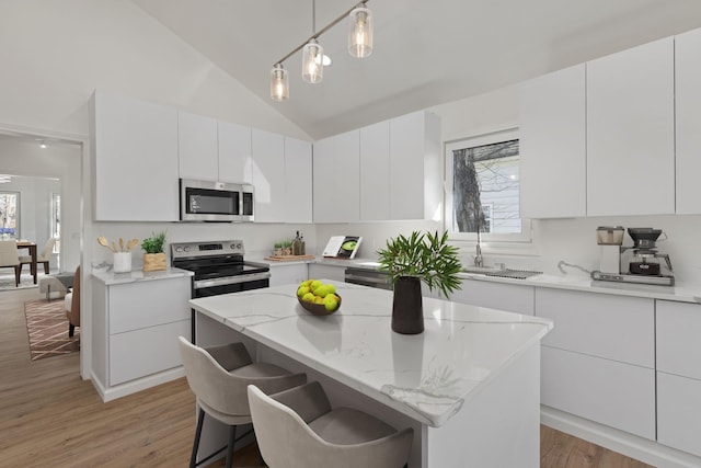  - kitchen with appliances with stainless steel finishes, light wood-style flooring, white cabinetry, a center island, and plenty of natural light