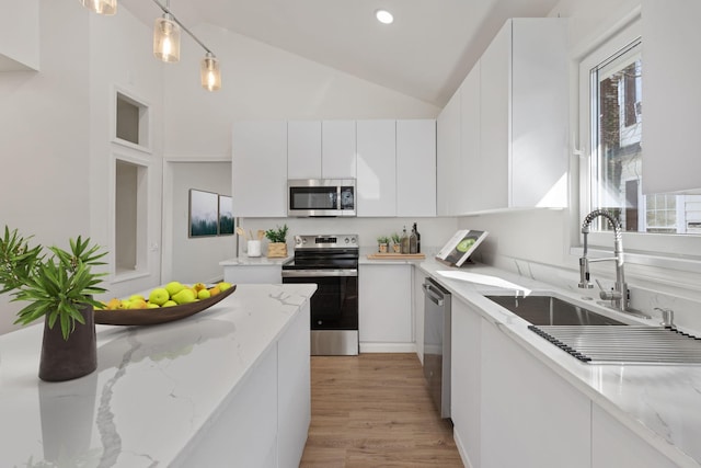 - kitchen with appliances with stainless steel finishes, white cabinetry, a sink, pendant lighting, and light wood finished floors