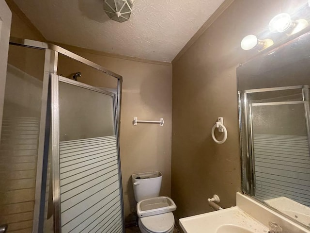 bathroom with sink, a shower with door, ornamental molding, a textured ceiling, and toilet