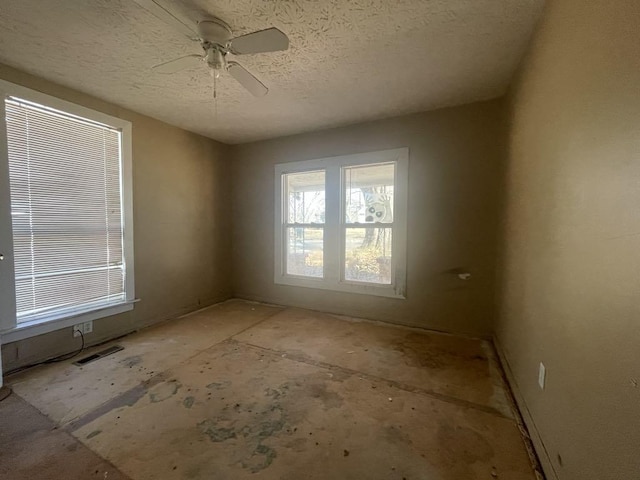 unfurnished room with ceiling fan and a textured ceiling