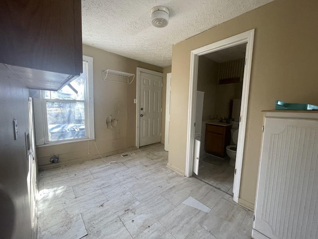 unfurnished bedroom with connected bathroom and a textured ceiling