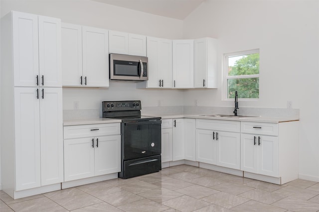  - kitchen with black electric range, stainless steel microwave, a sink, light countertops, and white cabinetry