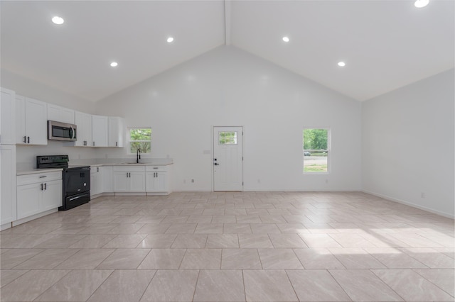  - kitchen featuring black electric range, stainless steel microwave, a sink, high vaulted ceiling, and light countertops