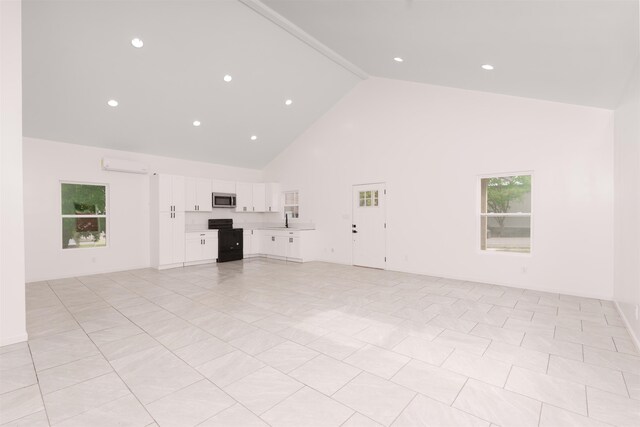  - unfurnished living room with high vaulted ceiling, a wall unit AC, and beamed ceiling