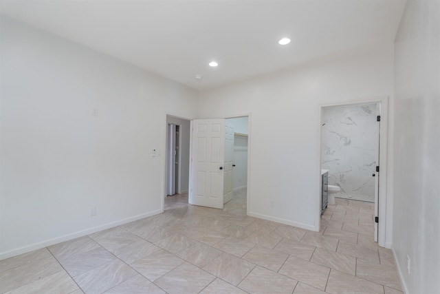  - unfurnished bedroom with a spacious closet, recessed lighting, ensuite bath, a closet, and baseboards