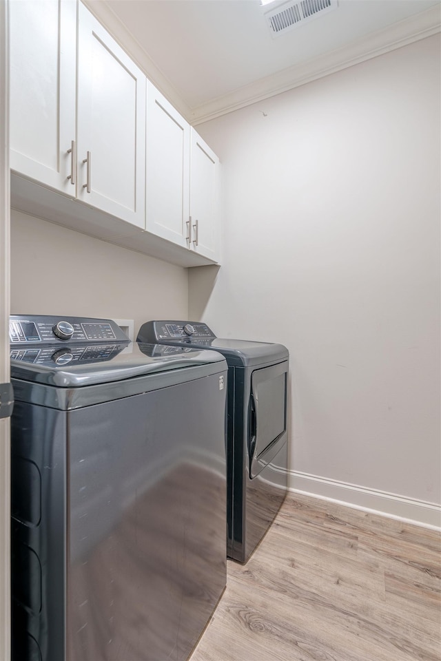 181 Silver Leaf Ln, Florence, AL - washroom with separate washer and dryer, cabinet space, ornamental molding, and light wood-type flooring