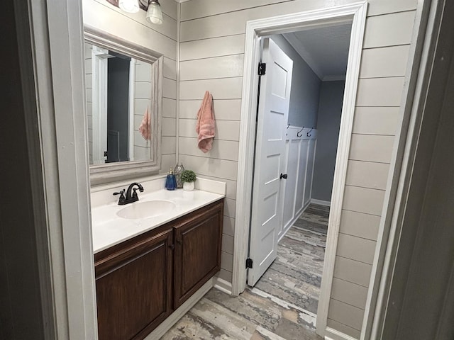 bathroom with wood walls, wood-type flooring, vanity, and ornamental molding