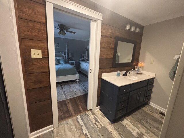 bathroom featuring ceiling fan, wood-type flooring, wood walls, and vanity