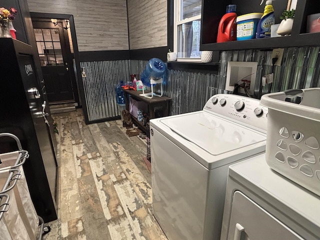 laundry room featuring hardwood / wood-style flooring, separate washer and dryer, and wooden walls